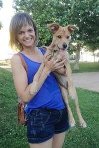Educadora canina de pie sujetando con las dos manos el cuerpo de su perro Baco, ambos mirando a la cámara