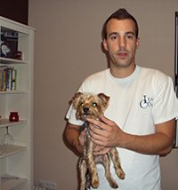 Educador canino de pie sujetando con las dos manos el cuerpo de su perro Curro, ambos mirando a la cámara