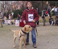 Niño de pie junto a su perro, con quien participó en el concurso la mascota del parque. El niño lleva una chaqueta y el numero 42. Ellos fueron finalistas y además forman parte del club de Agility de lealCan Adiestramiento canino