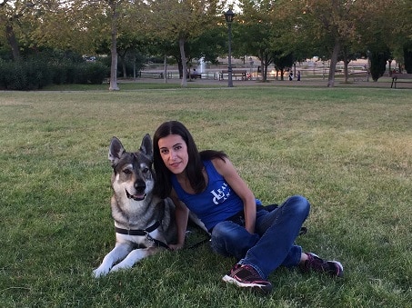 Adiestradora canina Aida Semiramis sentada en el césped junto a un perro