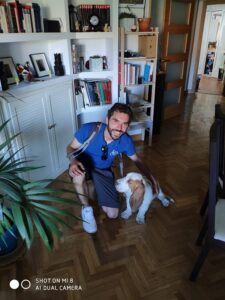 Educador canino apoyando su rodilla izquierda en el suelo y tocando a su perro Morris que se encuentra a su izquierda con la mano izquierda