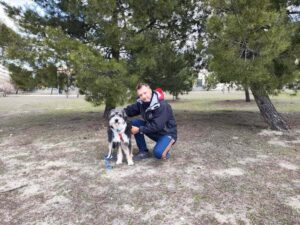 Adiestrador de perros de rodillas junto a su perro Kira